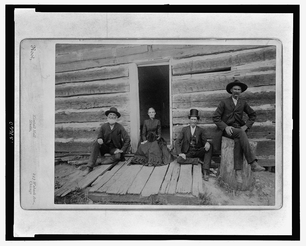 A partial view of the Lincoln cabin with open door and group of four including Mr. Thomas Lincoln's grandson John J. Hall, 1891 (Library of Congress)