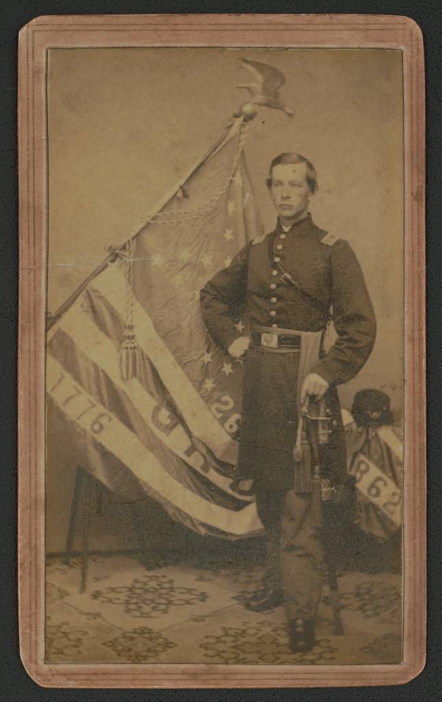 [Captain Jedediah Randall of Co. K, 26th Connecticut Infantry Regiment in uniform with sword in front of regimental flag], 1862 (Library of Congress)