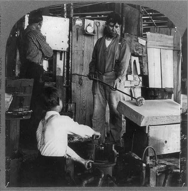 Dipping molten glass on blowpipe and shaping it on moulding stone - American Glass Bottle Industry, 1907 (Library of Congress)