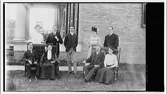 Family group alongside house by porch, 1920 (Library of Congress)
