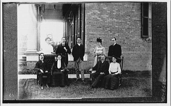 Family group alongside house by porch, 1920 (Library of Congress)