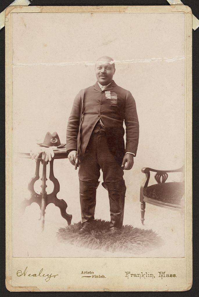 [Full-length portrait of an African American veteran and GAR member, standing on rug between table and chair], 1866 (Library of Congress)